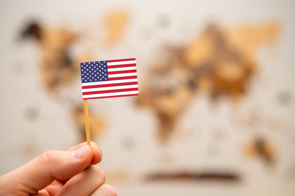 usa flag in mans hand on the world map background 2023 11 27 04 52 59 utc scaled