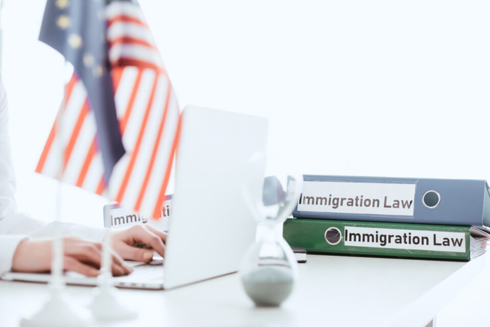 selective focus of woman typing on laptop near hourglass and american flag